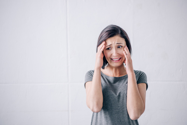 sad brunette woman with hands on head crying at home - Fotoğraf, Görsel