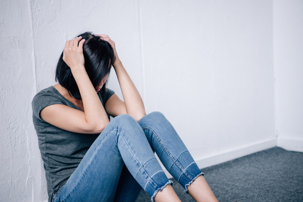 deprimovaná brunetka s rukama na hlavě sedět doma - Fotografie, Obrázek