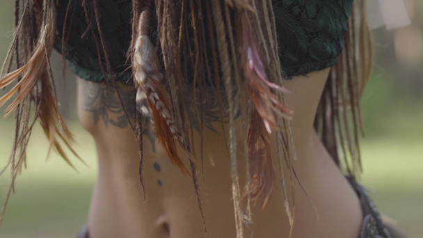 Close-up of dancing belly of attractive dryad or forest fairy with afro-braids and tattoo on the skin. The ancient ritual of forest creature. Performance of dancer in forest - Footage, Video