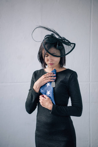 sad woman holding tag dog and folded american flag at home - Photo, Image