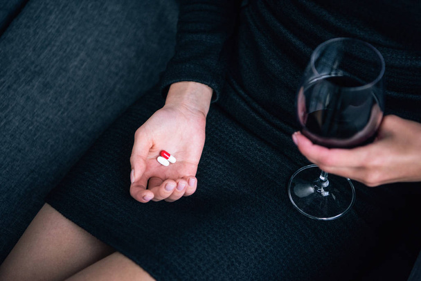 osittainen näkymä naisen viinilasin ja pillereitä kotona
 - Valokuva, kuva