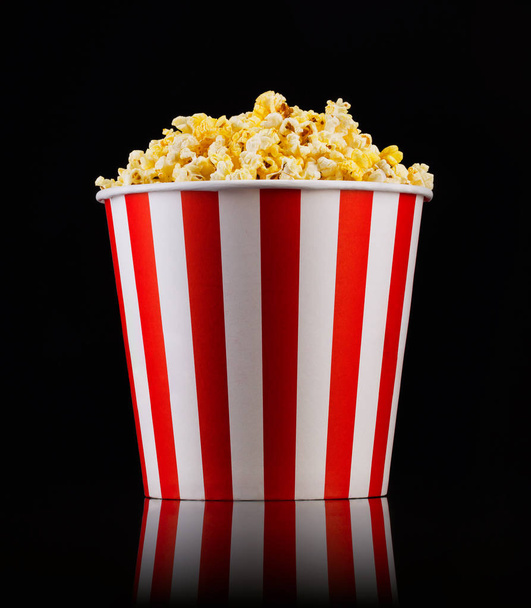 Paper striped bucket with popcorn isolated on black background - Foto, immagini