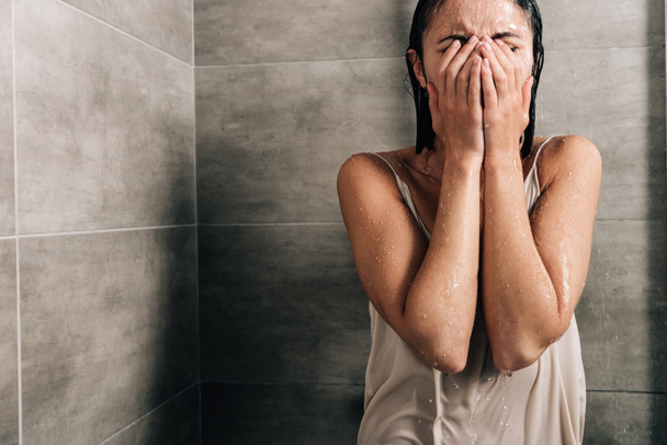 lonely sad woman covering face and crying in shower at home with copy space - Foto, afbeelding