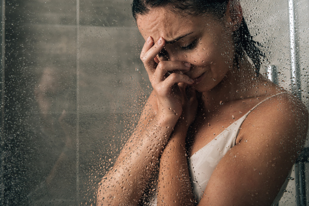 hermosa mujer triste cubriendo la cara y llorando en la ducha en casa
 - Foto, Imagen
