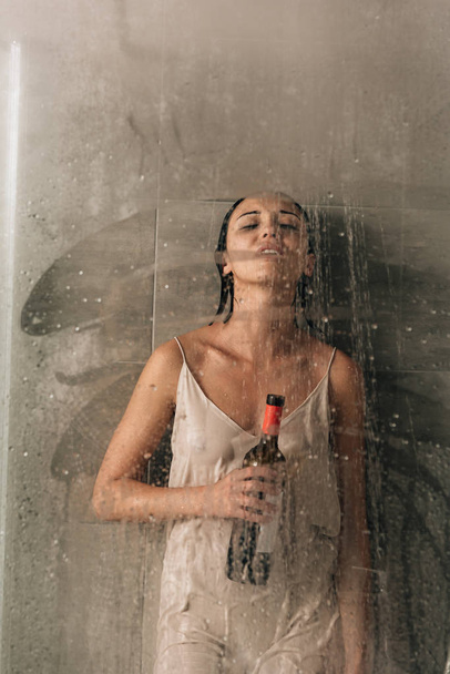lonely depressed woman in shower with wine at home - 写真・画像