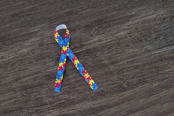 World Autism conciencia y orgullo día o mes con cinta de patrón de rompecabezas sobre fondo de madera
. - Foto, imagen