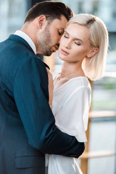 schöner bärtiger Mann im Anzug flirtet mit attraktiver Geschäftsfrau mit geschlossenen Augen  - Foto, Bild