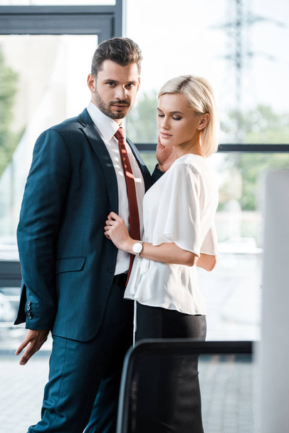 selective focus of handsome bearded man in suit standing and flirting with attractive businesswoman  - Φωτογραφία, εικόνα