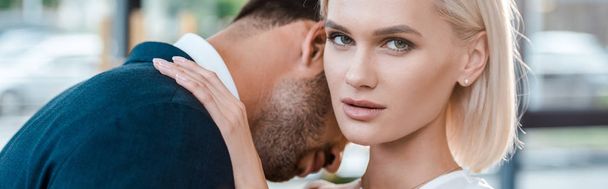 panoramic shot of attractive woman looking at camera while hugging man in office   - Fotoğraf, Görsel
