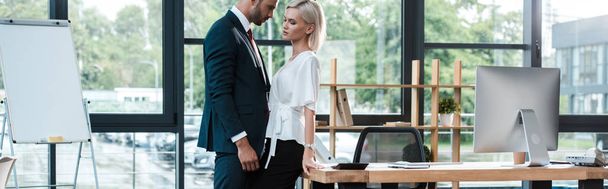 plano panorámico de hombre de negocios guapo tocando atractiva joven mujer mientras coquetea en la oficina
  - Foto, imagen
