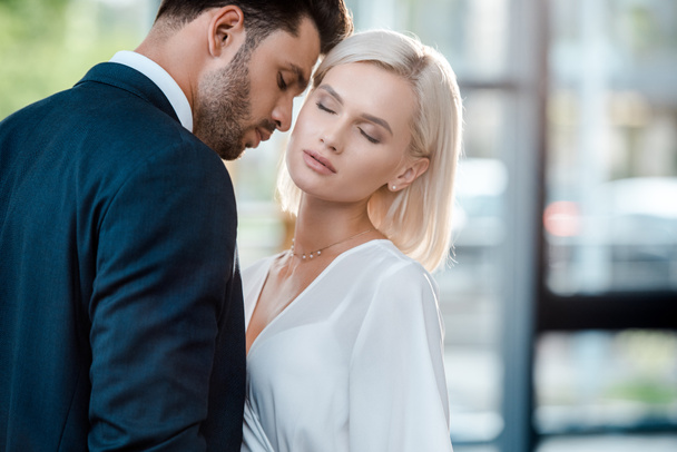 bearded man with closed eyes flirting with beautiful blonde coworker in office  - Valokuva, kuva
