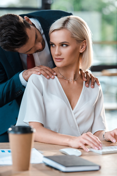 вибірковий фокус чоловіка, дивлячись на привабливу блондинку молоду жінку в офісі
  - Фото, зображення