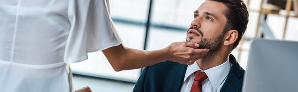 panoramic shot of woman touching face of passionate bearded man in office  - Photo, Image