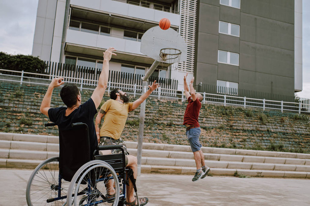 Человек в инвалидной коляске играет в корзину с друзьями
 - Фото, изображение
