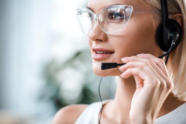 close-up de operador loira atraente em óculos tocando fone de ouvido
  - Foto, Imagem