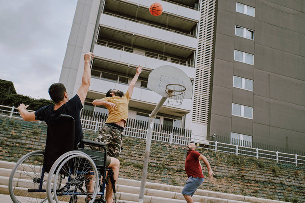 un homme en fauteuil roulant joue panier avec des amis
 - Photo, image