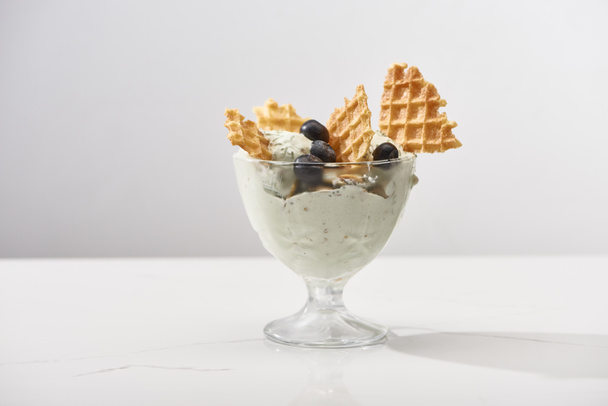 delicious pistachio ice cream with waffles and blueberries isolated on grey - Foto, afbeelding