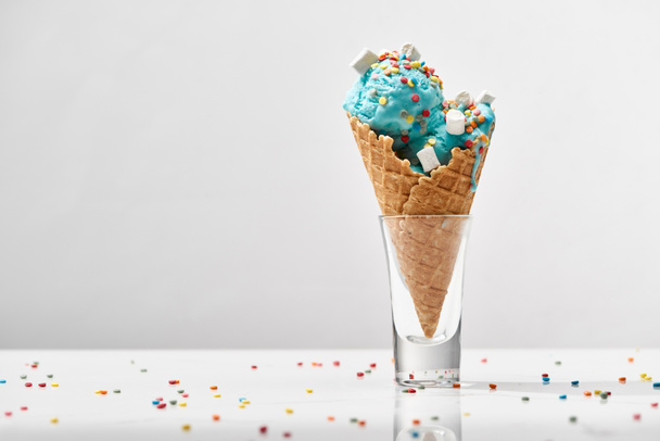 delicious sweet blue ice cream with marshmallows and sprinkles in crispy waffle cone isolated on grey - Foto, Imagen
