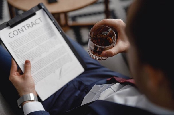 Selective focus of the man with glass of whisky reading contract - Φωτογραφία, εικόνα