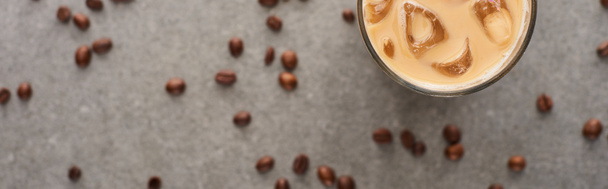 selective focus of ice coffee in glass and coffee grains on grey background, panoramic shot - Photo, Image