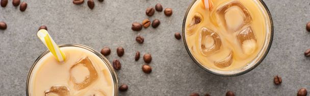 top view of ice coffee with straws and coffee grains on grey background, panoramic shot - 写真・画像