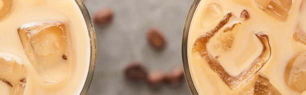 close up view of ice coffee in glasses and coffee grains on grey background, panoramic shot - Foto, afbeelding