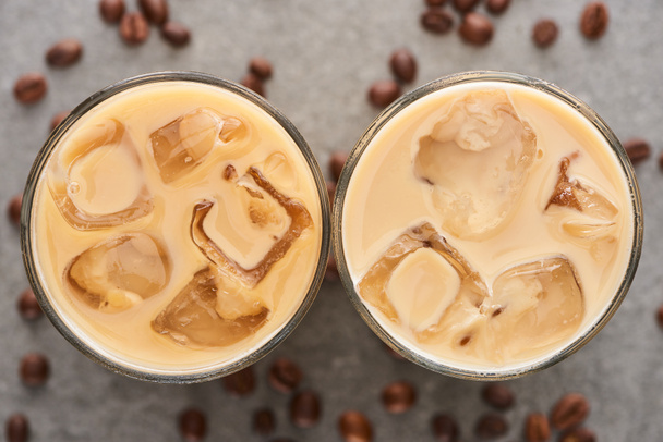 top view of fresh ice coffee in glasses and coffee grains on grey background - Foto, Imagen