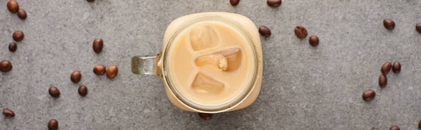 top view of ice coffee in glass jar near coffee grains on grey background, panoramic shot - Foto, Imagen