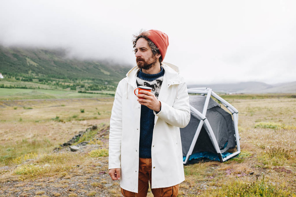 Serious rough outdoor man next to tent in iceland - Foto, imagen