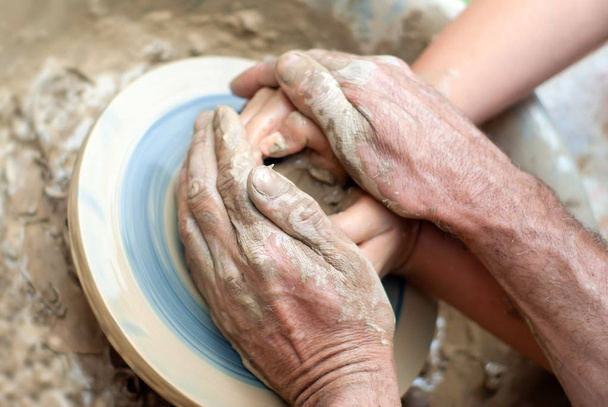 two pairs of hands create a clay product on a potter's wheel - Photo, Image