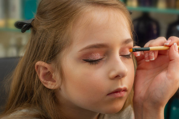 una niña haciendo maquillaje antes de actuar en el escenario. Preparación antes de la actuación en el vestidor
 - Foto, imagen