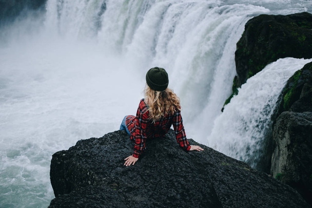 Pretty young female sits on edge of cliff iceland - 写真・画像