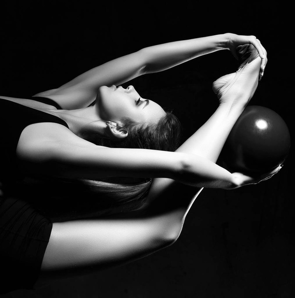 Young sporty woman doing gymnastics stretching fitness exercises workout with ball in sport club - Foto, Bild