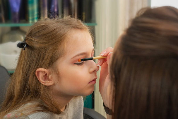 una niña haciendo maquillaje antes de actuar en el escenario. Preparación antes de la actuación en el vestidor
 - Foto, Imagen
