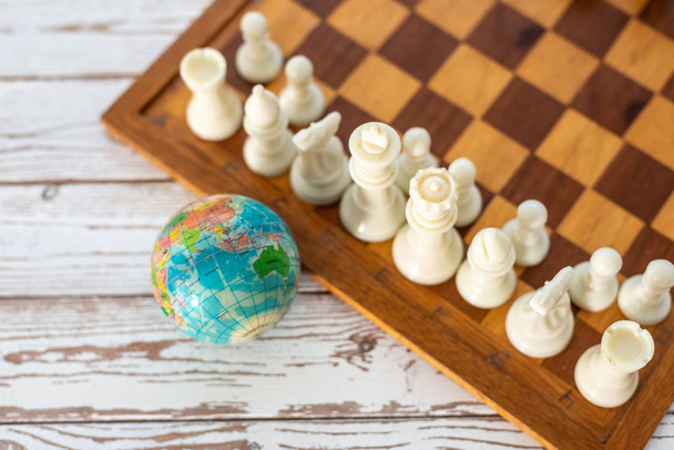 Utazás a világ. Sakkfigurák és világtérkép gömb. Sekély Dept - Fotó, kép