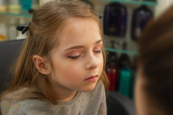 a little girl doing makeup before performing on stage. Preparation before the performance in the dressing room - Photo, Image