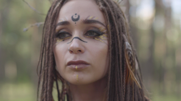 Porträt einer jungen Frau in theatralischem Kostüm und aus Waldläuten zusammengesetzt, die im Wald tanzen und Leistung zeigen oder Rituale durchführen - Filmmaterial, Video