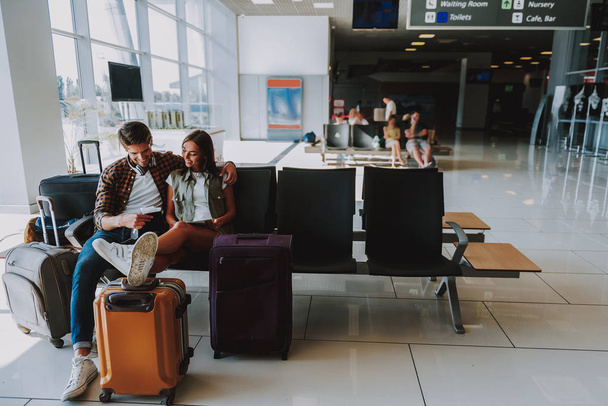 Smiling couple is waiting for plane indoors - Foto, imagen