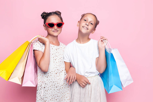 Two smiling teenage girls hold bags in their hands after a shopping trip - Foto, Bild