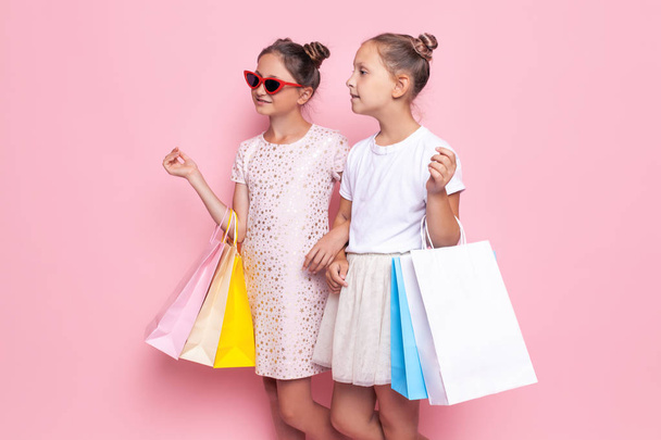 Deux adolescentes souriantes tiennent des sacs dans leurs mains après un voyage shopping
 - Photo, image