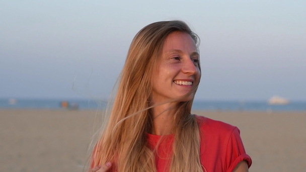 Πορτρέτο της χαρούμενη γυναίκα χαμογελά απολαμβάνοντας διακοπές στην παραλία στο ηλιοβασίλεμα σε αργή κίνηση - Πλάνα, βίντεο