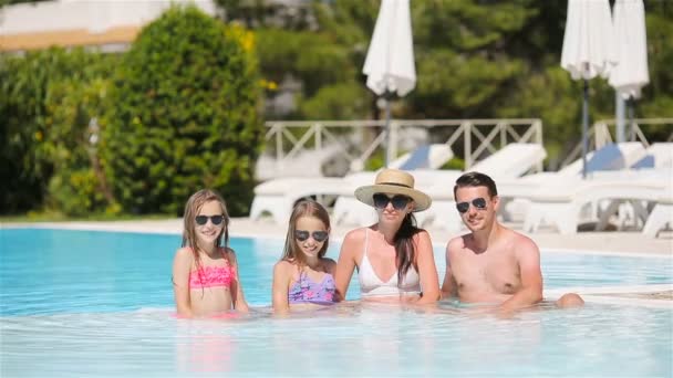 Familia feliz de cuatro en la piscina al aire libre - Metraje, vídeo
