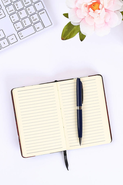A blank white notepad on a white desktop next to a coffee mug and a keyboard. - Φωτογραφία, εικόνα