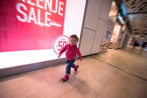 little girl running through shopping mall - Фото, изображение
