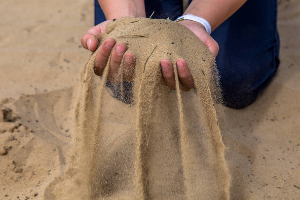Hands release the sand. Sand flows through the hands. Summer beach vacation - Foto, afbeelding