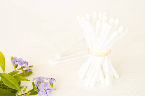 pamut rügyek egészségügyi ellátást a tisztítás lila virágok elrendezése lakás laikus stílusa a háttérben fehér fa - Fotó, kép