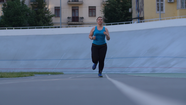 Mujer con sobrepeso corredor de entrenamiento en pista de estadio
 - Metraje, vídeo