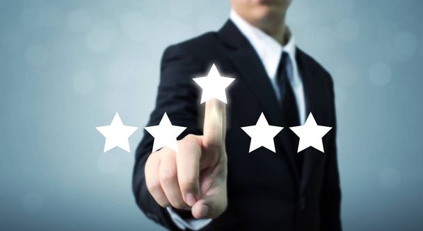 Бизнесмен указывает на пятизвездочный символ для повышения рейтинга компании - Фото, изображение