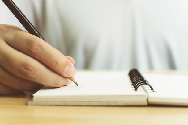 Hand van de mens met potlood schrijven op notebook - Foto, afbeelding