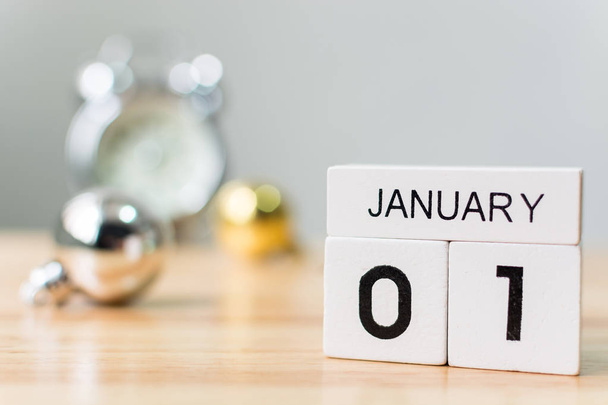 1. Januar, Kalenderholzblock mit Weihnachtskugeldekoration und Uhr auf Tisch, Neujahrsauflösung und Torkonzept - Foto, Bild